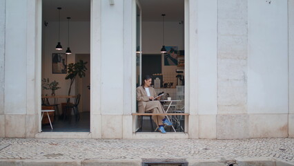 Trendy girl sitting cafe alone holding copybook. Businesswoman making notes