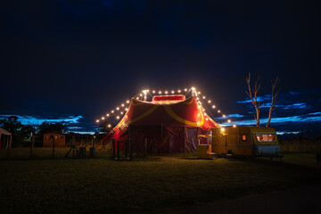 small circus tent with row of lights on in the evening © Luca