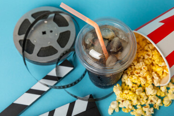 Tasty popcorn in buckets and cold cola drinks with cinema tickets, movie clapper and 3D eyeglasses...