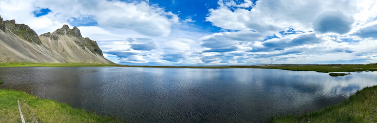 View of a beautiful lake with spectacular clouds and mountains in the Icelandic landscape.