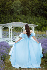 beautiful girl in a lavender field. Cute girl on purple background. Summer photo in the sun. a blue long dress