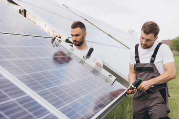 Two skilled workers or craftsmen wearing working gray uniforms, technicians are installing solar...