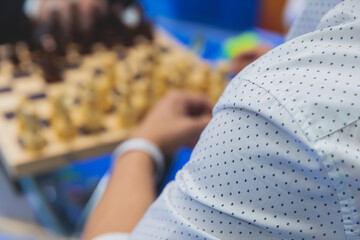 Chess tournament, kids and adults participate in chess match game in indoor hall, players of all ages play, competition in chess school club with chessboards on a table, wooden pieces