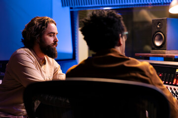 Musician songwriter composing a song with electro acoustic guitar, performing live in control room...