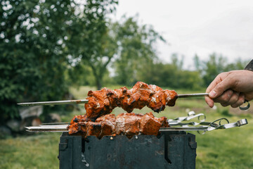 Man hand grilling barbecue with smoked pork at backyard on day. Family dinner outdoor style bbq activity