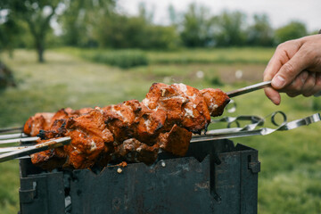 Man hand grilling barbecue with smoked pork at backyard on day. Family dinner outdoor style bbq activity
