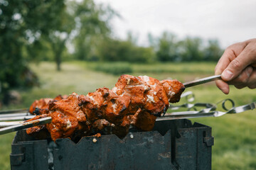 Man hand grilling barbecue with smoked pork at backyard on day. Family dinner outdoor style bbq activity