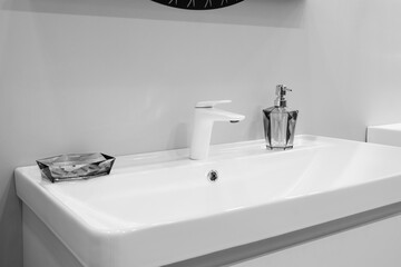 A sink with a soap dispenser and a small dish on top of it