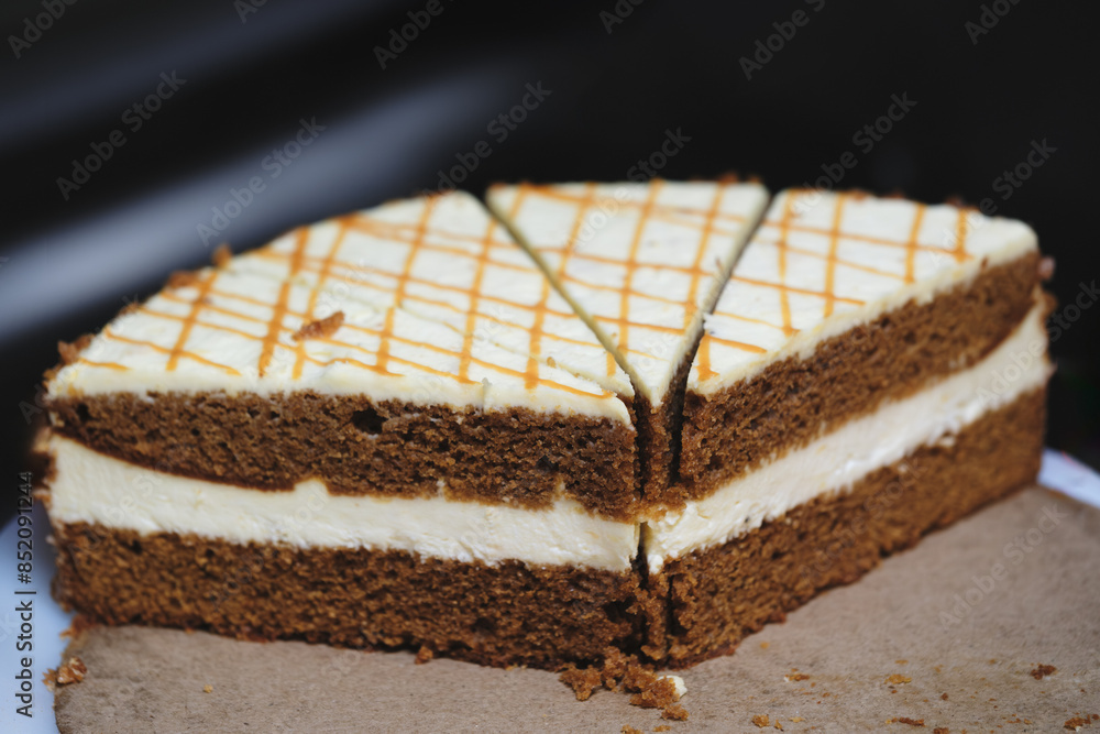 Poster a slice of cake with a white filling and brown frosting. the cake is cut in half and has a lattice d