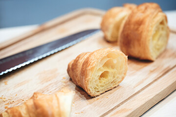 A knife is on a cutting board with a piece of pastry on it. The pastry is cut in half, revealing its inside