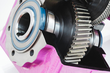 A close up of a gear with a blue and white circle in the middle. The gear is pink and has a black and silver color