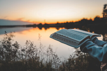 Woman hands holding bible and reading at river in the morning