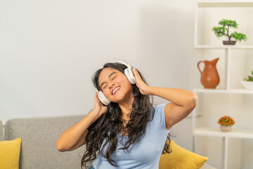 Woman enjoying music sitting on the sofa at home