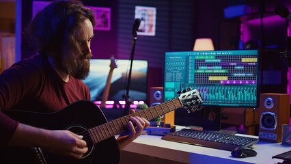 Artist playing guitar and uses DAW software interface to create music, looking at mastering...