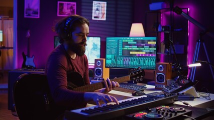 Musical composer recording his guitar tunes and adding piano key sounds, creating a beautiful song...