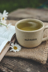 Cup with text BLESSED and open Bible in the garden, good morning