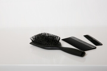 Used hair brush and combs with some hair on white table, head skin hygiene