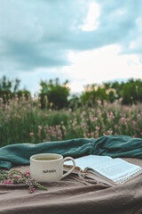 Cup with text BLESSED and open Bible in the garden, good morning