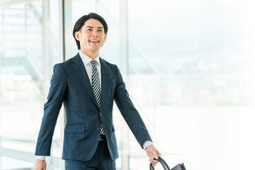 会社・オフィスに出勤・出社・通勤する若い男性アジア人ビジネスマン
