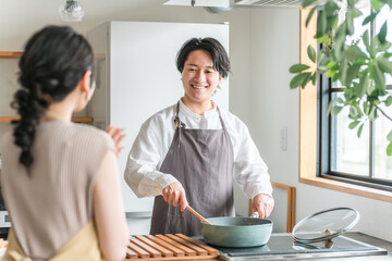 キッチンで料理・家事をする若いアジア人夫・（料理男子・自炊・共働き・ディンクス・趣味）
