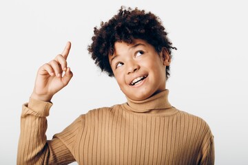 a young african american boy enthusiastically pointing at an object with a curious expression...
