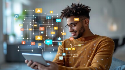 A young man in glasses uses a tablet device, with a digital network display behind him
