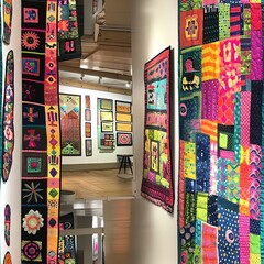 An art exhibit dedicated to textile arts, where vibrant patchwork quilts are showcased as examples of folk art, drawing connections between cultural history and modern craft