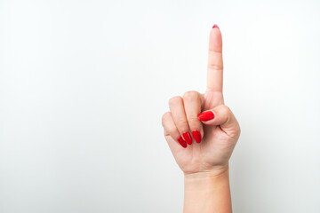 Raised woman's hand with bright red nail polish is making a pointing or touching gesture. Isolated...