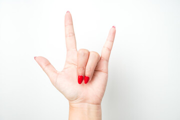 A woman's hand with bright red nail polish forms devil horns shape gesture as a sign of metal music.