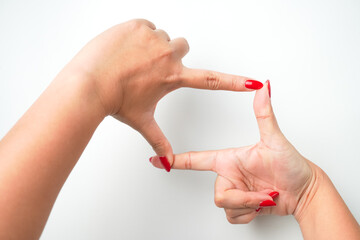 A woman's hand with bright red nail polish forms a square gesture using her index finger and thumb....