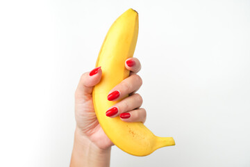 Hands of a woman with bright red nail polish holding large curvy banana fruit isolated on white...