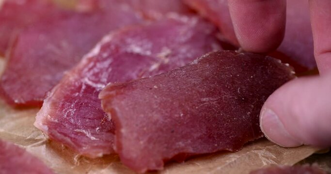 dried meat on paper in close-up, pieces of dried pork with spices and salt on crumpled paper