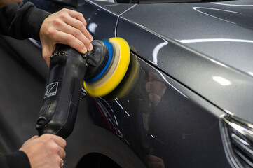 A master polishes the surface of a car body. 