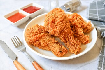 Fried chicken on a white plate with tomato sauce and chili sauce, 