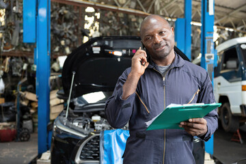 male worker talking on smartphone with customer in garage