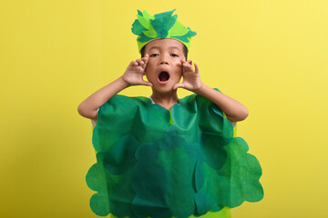 Cute child boy wearing vegetable costume isolated on yellow background