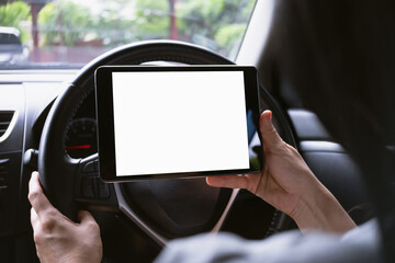 Woman sitting in a car and holding a tablet with blank screen.