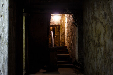 Exit from the basement to the stairs in an old gloomy building, exploring abandoned houses