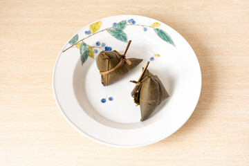 In Guangdong during the Dragon Boat Festival, steamed zongzi are placed on traditional Chinese-style plates, with the leaves wrapped in a triangular manner.