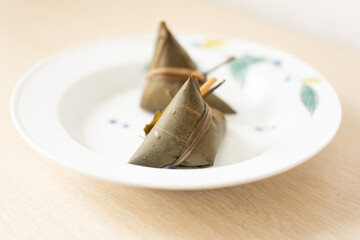 In Guangdong during the Dragon Boat Festival, steamed zongzi are placed on traditional Chinese-style plates, with the leaves wrapped in a triangular manner.
