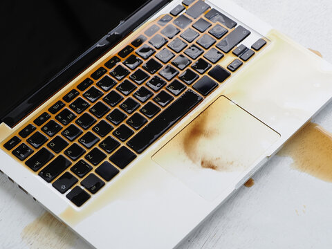Coffee spilled on the laptop keyboard. Damaged wet computer notebook. 