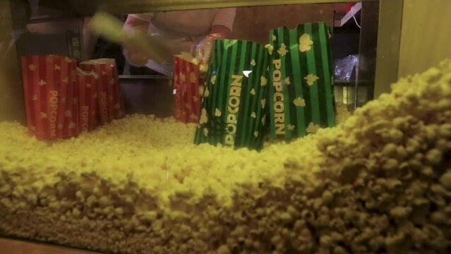 Hands of a worker scooping movie popcorn into popcorn bags 