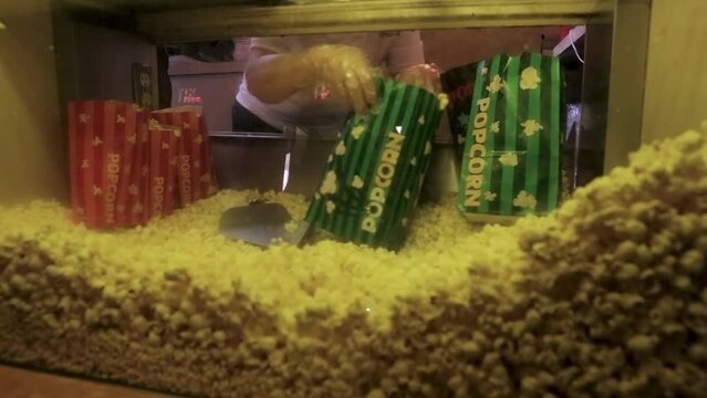 Movie popcorn scooped and poured into popcorn bags 