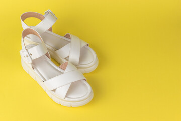 White Summer Sandals on Vibrant Yellow Background - Fashionable Women's Footwear Display