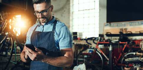 Bicycle, man and phone for shop, garage and small business of mechanic, engineer or entrepreneur. Proud, owner or person with service maintenance for bike, inspection or transport with mobile app