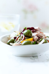 Salad with tuna, green olives and cherry tomatoes. Bright wooden background. Close up. Copy space.	