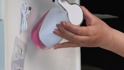 The woman makes a review of the dispenser for liquid soap. Demonstrates governing bodies. Vertical video