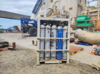 high pressure argon cylinder bottles inside the basket rack. concept illustration of safe storage of tubes in factory industrial area.