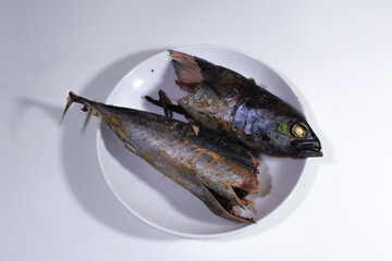 Pindang fish is broken in half on a white plastic plate