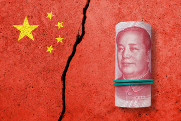 One hundred yuan note on a cracked concrete background. China finance, real estate and debt crisis....